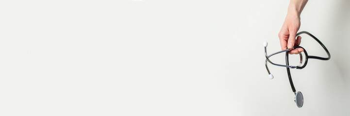 female hand holds a stethoscope on a white background. Banner