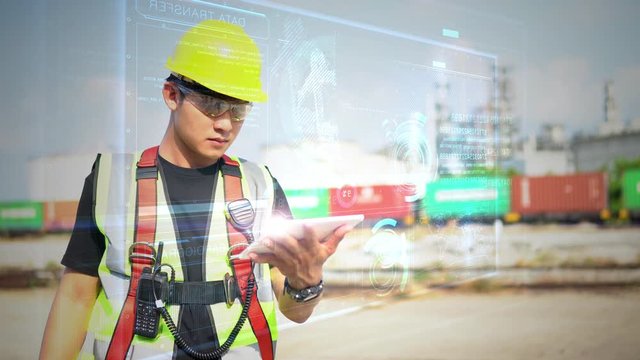 Male Industrial Engineer Works with glasses shows a conceptual hologram Industrial robot arm consisting on blurred background of large industry 