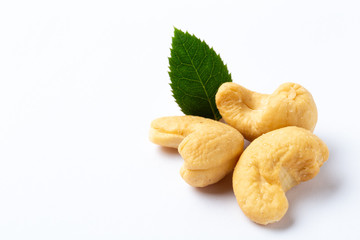 Cashew nuts with a green leaf on white background