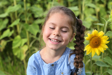 horizontal photo of a six year old girl smiling with her eyes closed on a background of sunflowers