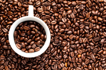 White cup with coffee beans on a background of coffee beans