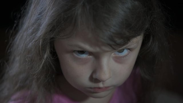 Angry child emotion. Angry little girl on a black background.