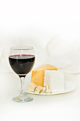 Glass of red wine and cheese on a plate