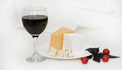 Glass of red wine and cheese on a plate