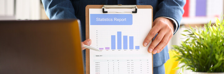Male arm in suit show stats graphic clipped to pad in office closeup. Stock exchange market advisor...