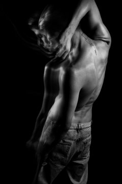 Naked back in black and white. Handsome young man standing on black background. Emotional portraits. negation. Symbolic metaphorical images