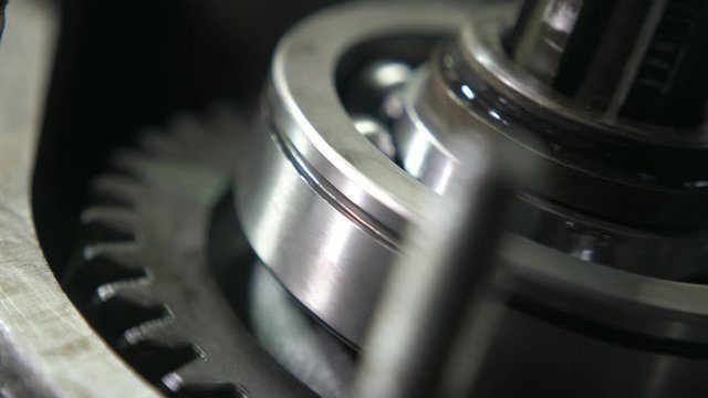 Bright ball-bearing and large cogwheel rolling fast in a modern car transmission