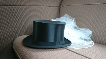 Marriage accessories and wedding symbols - bridal veil and vintage top hat on the backseat of a...