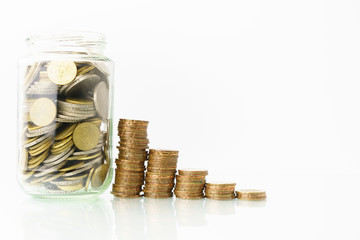 conceptual money growing, increasing finance situations, time cost money. stacked money coins and a glass bottle of coins againt white background . free copy space for your text