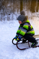 Little boy enjoying a sled. Children sledding. The kid is riding a sleigh. A child plays outside in the snow.