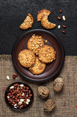 Homemade peanut cookies on a brown plate with raw peanuts in background