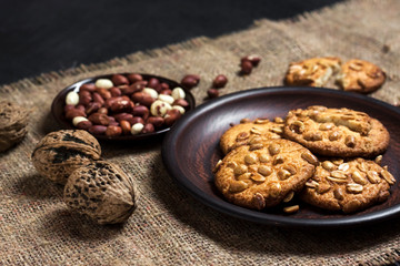 Homemade peanut cookies on a brown plate with raw peanuts in background