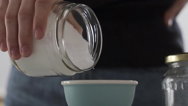 Slow motion close shot as pouring out sugar, birch sugar to measure it for baking.