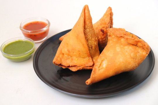 Vegetarian Aloo samosa or samosas. Indian special traditional street food. Famous Indian Punjabi samosa filled with spicy boiled potato mixture. served with green and red chutneys. Copy space.