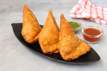 Vegetarian Aloo samosa or samosas. Indian special traditional street food. Famous Indian Punjabi samosa filled with spicy boiled potato mixture. served with green and red chutneys. Copy space.