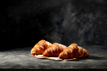 Dark mood background and fresh croissants on board.Free space for your decoration and breakfast time. 