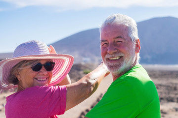 couple of seniors in a holiday together having fun - two mature people looking at the camera smiling and laughing - woman inndicating something with her arm