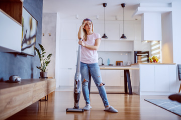 Fototapeta na wymiar Tired pensive gorgeous caucasian blond housewife dressed casual standing in her apartment and leaning on steamer.