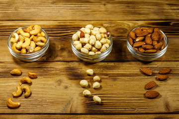 Assortment of nuts on wooden table. Almond, hazelnut and cashew in glass bowls. Healthy eating concept