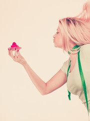 Woman with measuring tape holding sweet cupcake