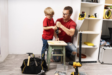 Father teaches son to work with a hand drill.