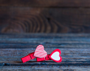 Two little red clothespins hearts. On a wooden background. Love