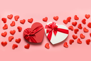 Valentines day greeting card. Two red gift boxes heart shaped and many little hearts on pink. View from above. Space for text.