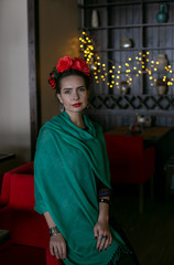 vertical photo of a girl in bright clothes and with bright makeup who stands looking directly at the camera