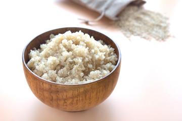 Cooked quinoa in wooden bowl  on  brown background