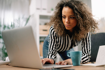 Fototapeta premium Young businesswoman in office. African beautiful woman using lap top. 