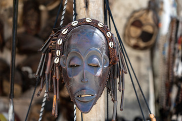Traditional african wooden masks hanging for sell on the street market on the island of Zanzibar, Tanzania, Africa, close up - obrazy, fototapety, plakaty