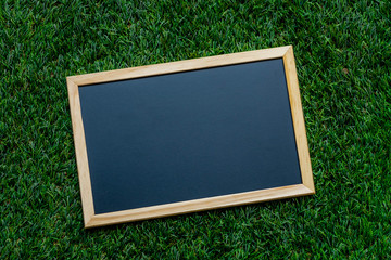 A small blackboard placed on an artificial grass Background for educational illustration.