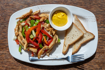 Roasted chicken fillet with vegetables and bread on a white plate, closeup