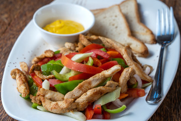 Roasted chicken fillet with vegetables and bread on a white plate, closeup