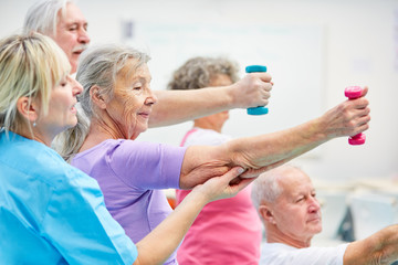 Therapist helps seniors with dumbbells