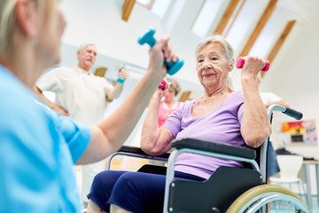 Senior woman in wheelchair doing workout with dumbbells