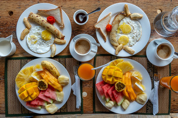 Tropical breakfast of fruit, coffee and scrambled eggs and banana pancake for two on the beach near sea