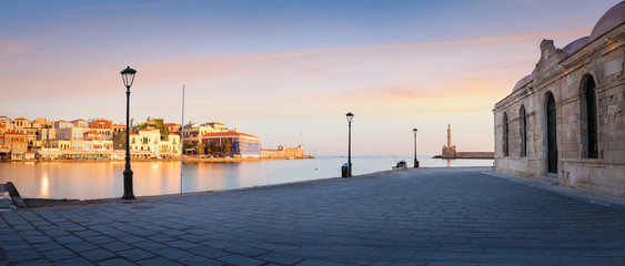 Panorama of Old harbor of Chania with the lighthouse, bench and lamp with beautiful sky at sunrise, Crete, Greece