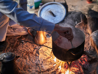 Bedouin man cooking traditional bedouin meal on fire in a tent