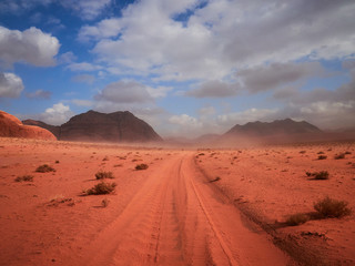 Fototapeta na wymiar Beautiful Scenery Scenic Panoramic View Red Sand Desert and Ancient Sandstone Mountains Landscape in Wadi Rum, Jordan during a Sandstorm