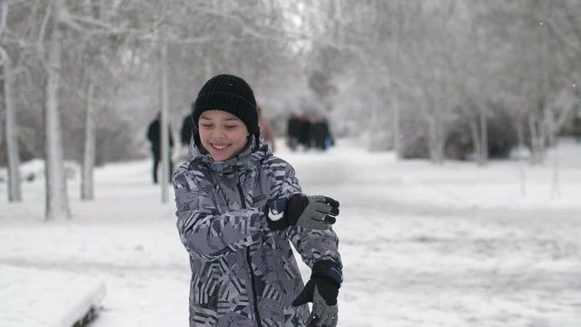 Joyful boy dancing actively and waving his hands aside in airy park in winter
