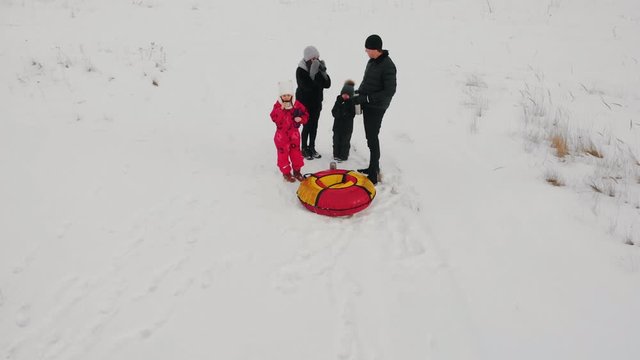 Family standing in the middle of the snowy field and drinking hot drinks from the termos