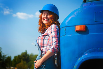 photo of a girl in denim overalls standing near a bumper of a truck