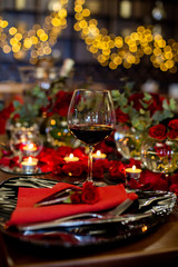 a glass of red wine stands on a table decorated for the holiday
