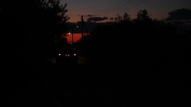 Lonely car drives through the night town blinking lights. Slow motion. Country road in Cyprus