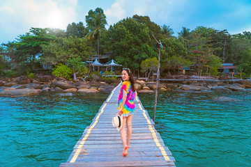 girl in a colorful  dress posing on the wood bridge to the sea with relaxing day by holiday trip