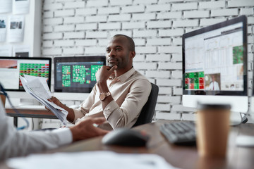 Strategies to Grow Money. Two diverse colleagues traders discussing ideas while sitting in the...
