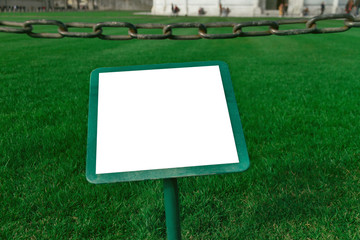 place for writing text, scoreboard in a green frame, on the grass, fenced with a metal chain