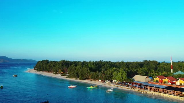 flying over an atoll island tropical Gili paradise island, turquoise ocean and blue sky with clouds in the background.