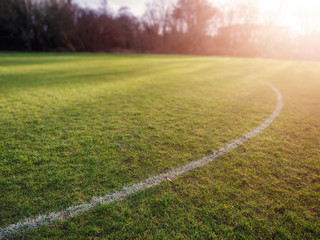 Obraz premium Line on a grass for outdoors sports like soccer, rugby hurling at sun set, Warm sun flare, Concept active sport facility.